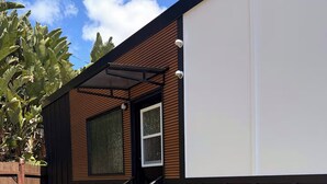 A backyard with artificial grass, a wooden deck, and a small outdoor seating area. - ArtNest: Full Kitchen & bath, Dishwasher, W/D, Firepit, Private, Parking, Safe (Escondido)