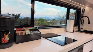 A modern kitchen with a large window, a coffee machine, a tablet, and a sink. - ArtNest: Full Kitchen & bath, Dishwasher, W/D, Firepit, Private, Parking, Safe (Escondido)