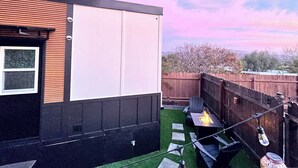 A modern house with a large white garage door, a small window, and a fire pit in the backyard. - ArtNest: Full Kitchen & bath, Dishwasher, W/D, Firepit, Private, Parking, Safe (Escondido)