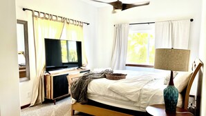 Ein Schlafzimmer mit einem Bett, einem Fernseher, einem Deckenventilator und einer Lampe.
