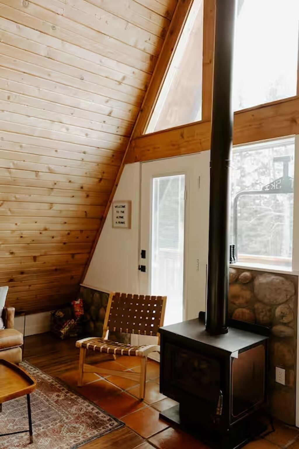 Een gezellige kamer met een schuine kap, een stenen openhaard, een houten stoel en een vloerkleed.