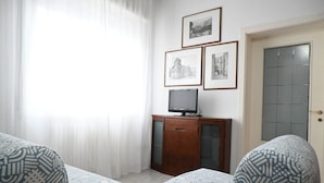 Ein Zimmer mit zwei gemusterten Sofas, einer Holzkabine mit Fernseher und drei gerahmten Bildern an der Wand.