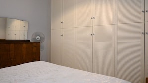 Ein Schlafzimmer mit einem Bett, einer Holzkommode und einem großen Kleiderschrank mit mehreren Türen.