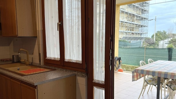 Eine Küche mit Holzausstattung, einem Spülbecken und einem Fenster mit Vorhängen.