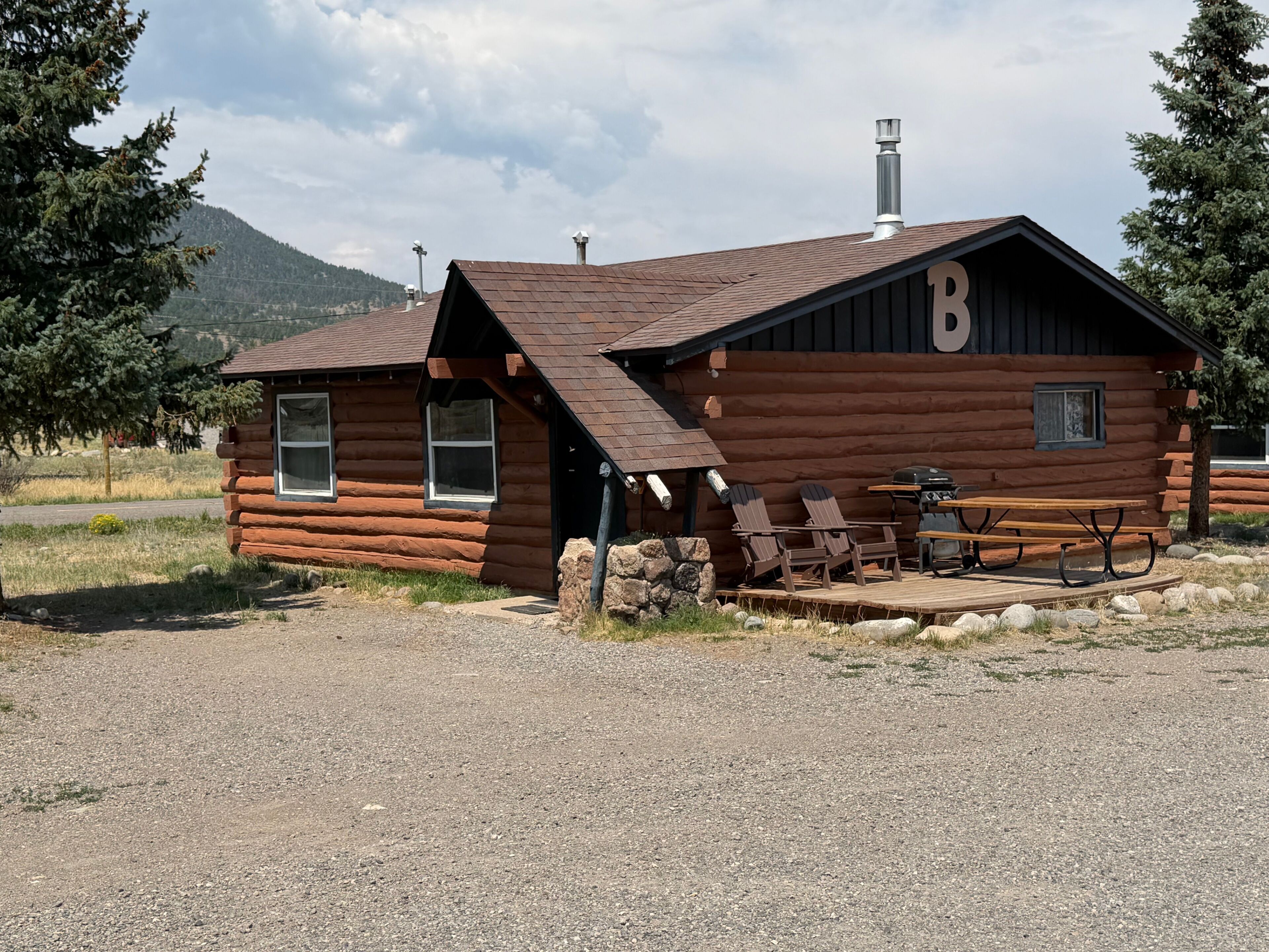 A log cabin with a deck, outdoor seating, and a chimney.