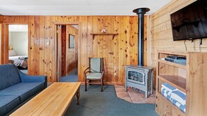 A cozy room with wooden walls, a sofa, a chair, a table, a fireplace, and a television. - "B" Bear Cabin - South Fork (South Fork)
