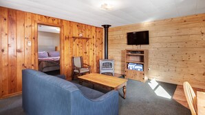 A cozy room with a wooden interior, a sofa, a table, a chair, a television, and a fireplace. - "B" Bear Cabin - South Fork (South Fork)