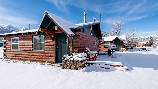 Eine Blockhütte mit verschneitem Dach und einer Holterrasse.