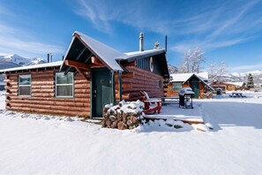 En timmerstuga med ett snötäckt tak och en träveranda.