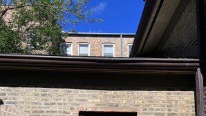 A brick building with a dark grey door, a small window, and a wall-mounted light fixture. - Stunning Coach House in Evanston, near Lake and Northwestern University (Evanston)