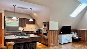 A modern kitchen with a central island, built-in appliances, and a lofted seating area. - Stunning Coach House in Evanston, near Lake and Northwestern University (Evanston)