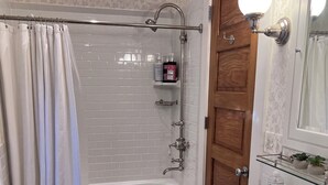 A bathroom with a bathtub, a sink, and a shower area. - Stunning Coach House in Evanston, near Lake and Northwestern University (Evanston)