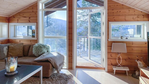 A cozy cabin interior with a wooden interior, a sofa, a table with a glass, and a fox statue. - Cozy home in Stryn with sauna (Stryn)