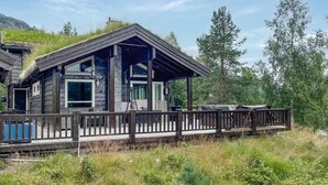 A cabin with a wooden deck, stone walls, and a mountain backdrop. - Cozy home in Stryn with sauna (Stryn)