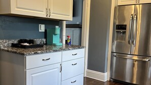 A kitchen with white cabinets, a stainless steel refrigerator, and a granite countertop. - Historic 3 Bedroom home, steps away from the Capitol, Clay Center and Ballpark. (Charleston)