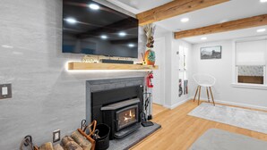 Una sala de estar moderna con chimenea, televisor montado y vigas de madera en el techo.