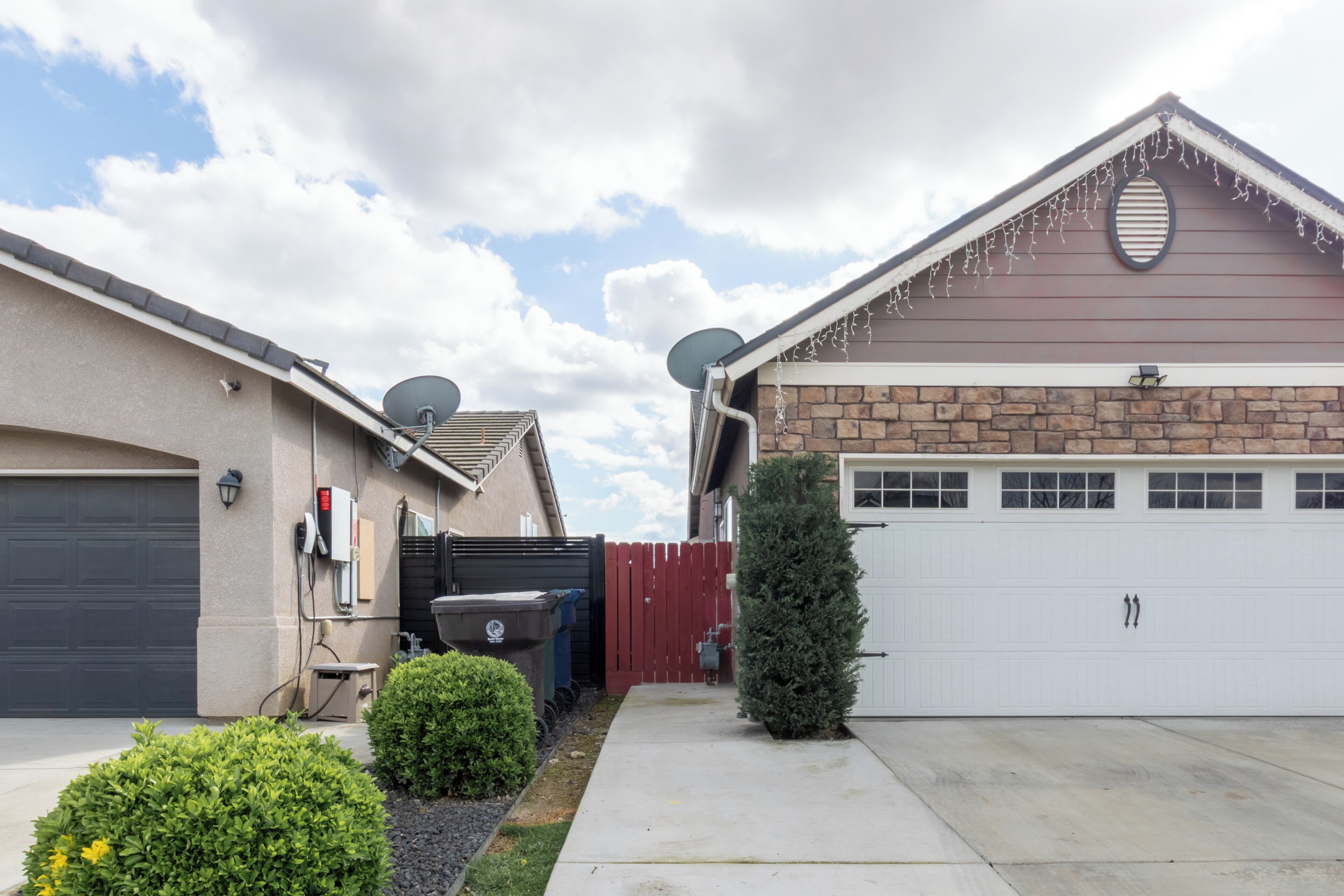 A residential garage with a white door, a brick exterior, and satellite dishes.