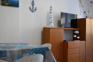 Ein Schlafzimmer mit einem Bett, einem Schminktisch, einem Fernseher und einer Wanddekoration.