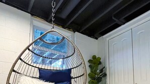 A room with a hanging chair, a potted plant, and a white door.