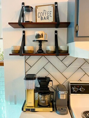 Eine Küche mit einer Kaffeebar-Beschilderung, einer Kaffeemaschine, einem Mixer und einem Herd.