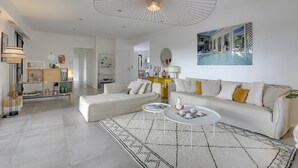 Un salón moderno con un sofá blanco, una mesa de centro y una lámpara de techo grande.