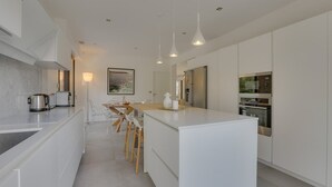 Una cocina moderna con armarios blancos, una isla central y electrodomésticos de acero inoxidable.