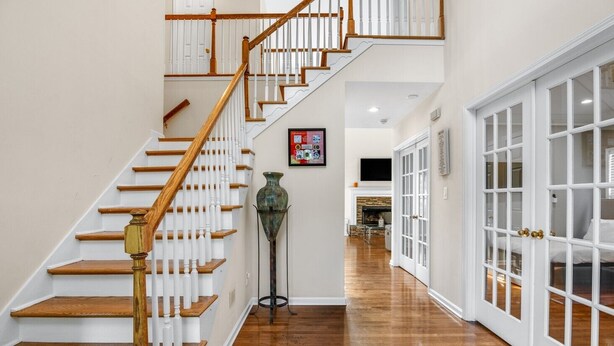 A staircase with wooden steps and white railings, leading to a room with a fireplace and a bed. - New! Lux Mansion, 5 BR 4 BA, Heated Pool, Sleeps 12+ (Fayetteville)