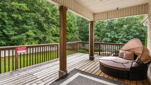 A covered outdoor deck with a wooden railing, a single wicker chair with a canopy, and a 'Maximum Capacity' sign. - New! Lux Mansion, 5 BR 4 BA, Heated Pool, Sleeps 12+ (Fayetteville)