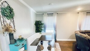 A modern living room with a dining area, a teal storage unit, and a large plant. - The Beauty Lounge Guest House (Manchester)