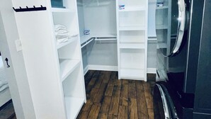 A corner of a room with a built-in white shelving unit, a black refrigerator, and a wooden floor. - The Beauty Lounge Guest House (Manchester)