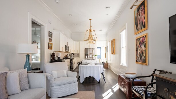 Un salón amplio con sofá, sillón, mesa de comedor y zona de cocina.