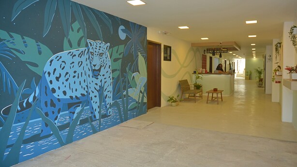Eine Hotelhalle mit einer großen Leopardenmalerei an der Wand, einem Empfangstresen und mehreren Sesseln.