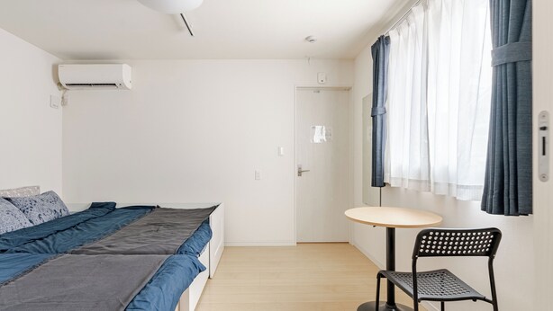 A minimalist bedroom with a bed, a small table, and a chair. - EXPO 22 min,USJ 26 min,Kaiyukan 18 min,Solaniwa 6 min, Kyocera Dome 17 min (Osaka)