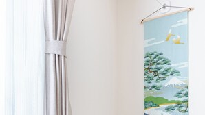 A room with a round wooden table and a white chair, a curtain, and a wall-mounted artwork depicting a nature scene. - EXPO 22 min,USJ 26 min,Kaiyukan 18 min,Solaniwa 6 min, Kyocera Dome 17 min (Osaka)