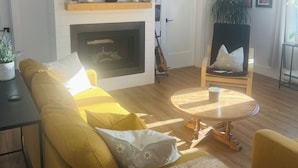 Ein Wohnzimmer mit einer Couch, einem Couchtisch, einem Kamin, einem Fernseher und einem Sessel.