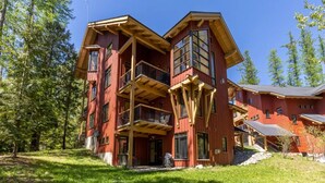 Une cabane en bois à plusieurs étages, dotée de balcons et entourée d’arbres.