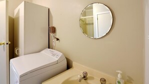 A bathroom with a toilet, sink, and mirror. - Okiwi Bay Cosy Cottage (Ōkiwi Bay)