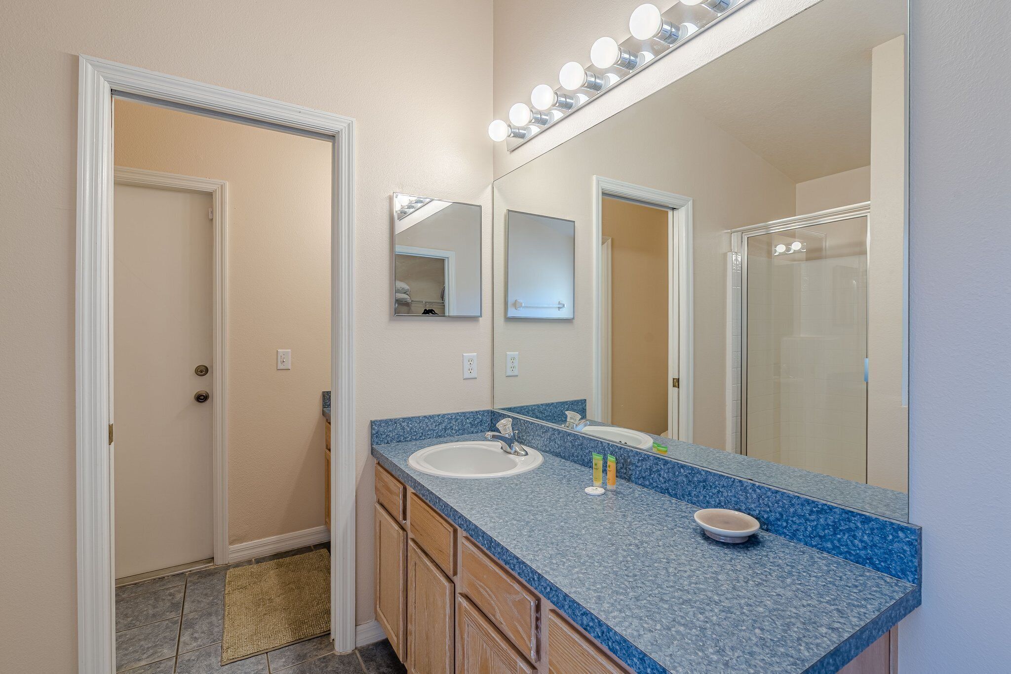 A bathroom with a blue granite countertop, a white sink, and a large mirror with lights above it.