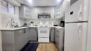 A compact kitchen with white cabinets, a stove, a microwave, and a refrigerator. - New Private Spacious & Modern Apartment near Square One and Downtown Mississauga (Mississauga)