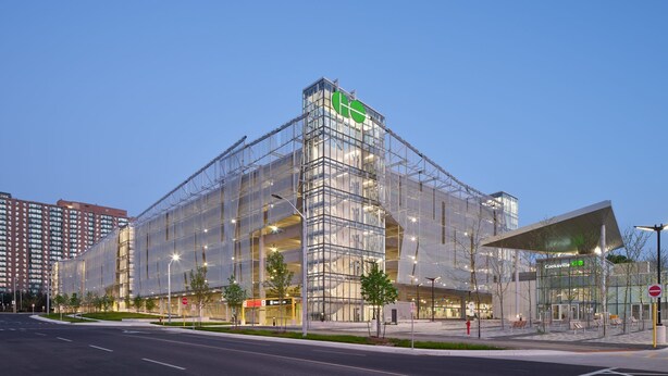 A modern building with a glass facade, a green logo at the top, and a covered entrance area. - New Private Spacious & Modern Apartment near Square One and Downtown Mississauga (Mississauga)