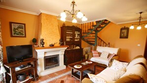 A living room with a fireplace, a television, a sofa, a coffee table, and a staircase. - Holiday Home 'Supereda' with Mountain View, Private Terrace and Wi-Fi (San Juan de Parres)