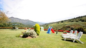 A grassy outdoor area with a slide, lounge chairs, and a small playhouse. - Holiday Home 'Supereda' with Mountain View, Private Terrace and Wi-Fi (San Juan de Parres)