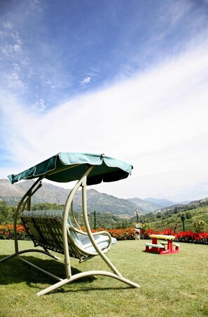 Una silla de jardín con toldo, una mesa de picnic y vistas a montañas.