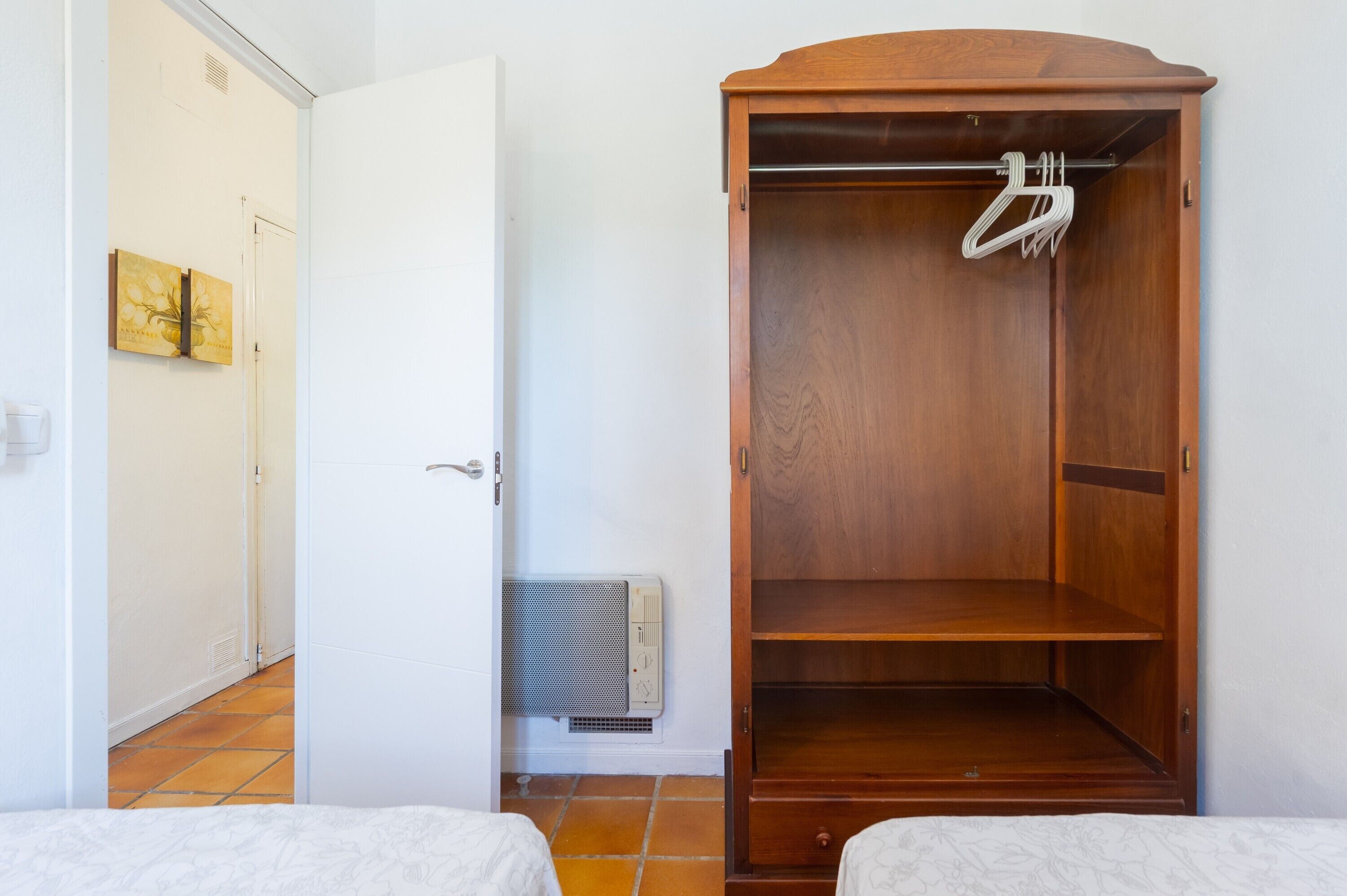 Une pièce avec une armoire en bois, un radiateur et une porte qui donne sur une autre pièce.