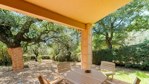 An outdoor patio with a table and chairs, surrounded by trees and greenery. - Rural House El Chopo with Mountain Views, Terrace, Shared Pool, and Parking (Alajar)