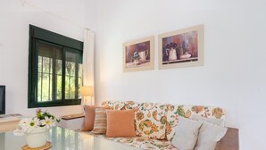 A living room with a sofa, a coffee table, a window, and two framed paintings on the wall. - Rural House El Chopo with Mountain Views, Terrace, Shared Pool, and Parking (Alajar)
