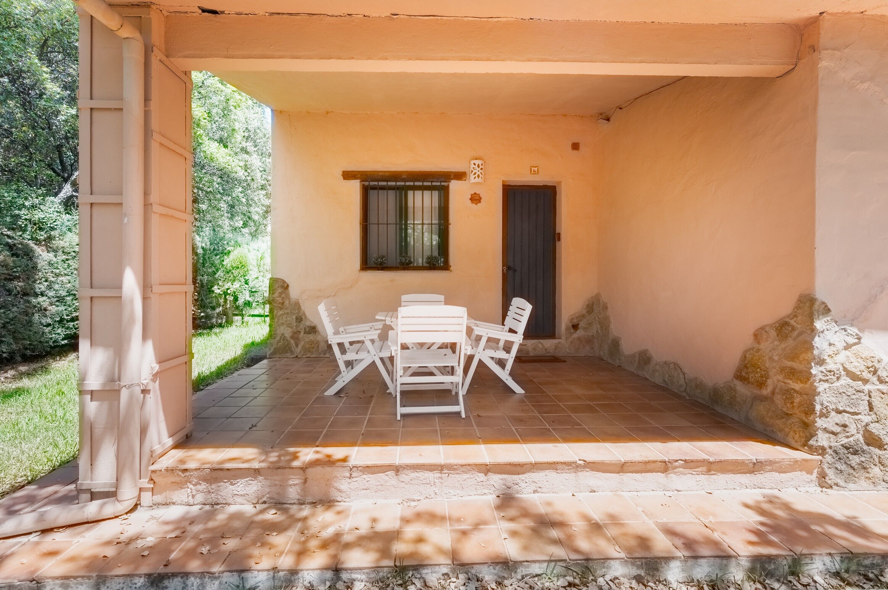 Une terrasse couverte avec une table et des chaises, une fenêtre et une porte.