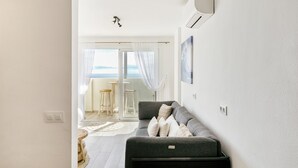 Una sala de estar moderna con un sofá gris, un ventanal con vistas y un equipo de aire acondicionado instalado en el techo.