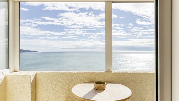 Una habitación con vista al mar, una mesa redonda y dos sillas.