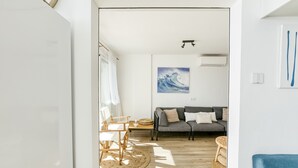 Una sala de estar moderna con un sofá, una mesa de comedor con sillas, un tapete redondo y un cuadro en la pared.